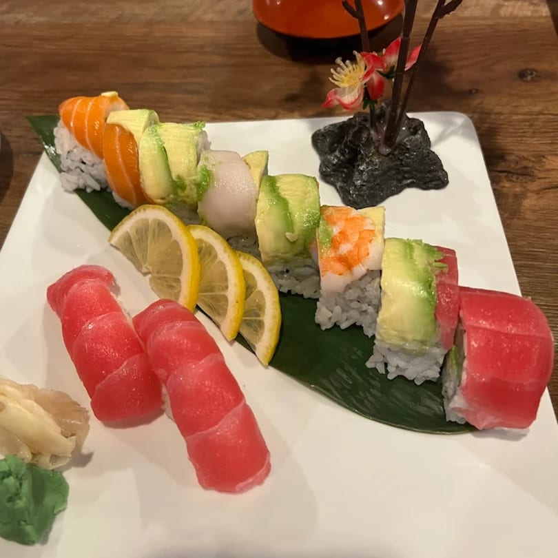 A sushi platter with various rolls, tuna nigiri, lemon slices, wasabi, and ginger.
