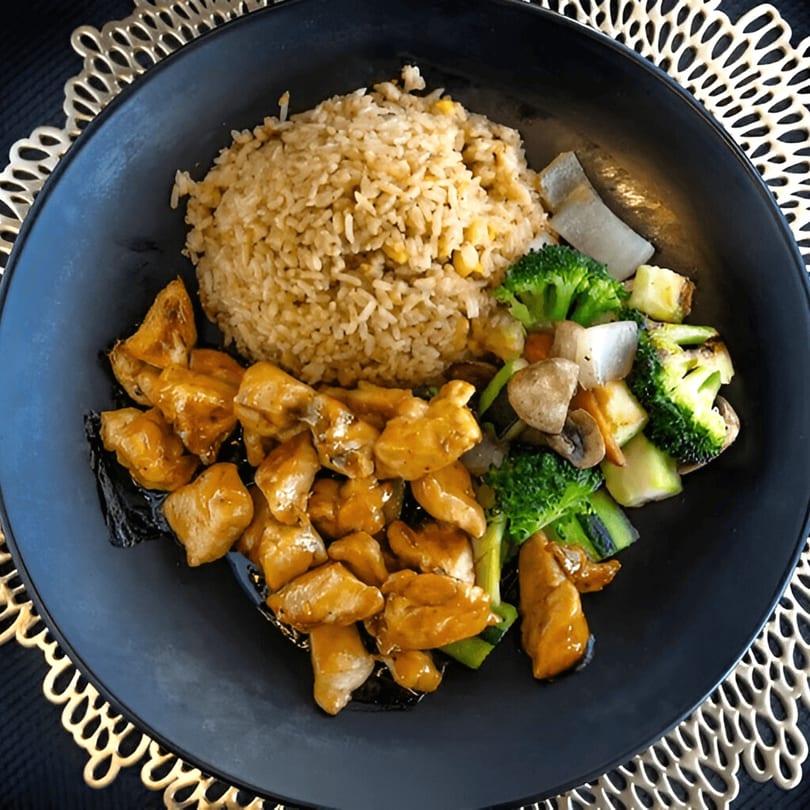Osaka Hibachi's chicken teriyaki with fried rice and mixed vegetables on a black plate.