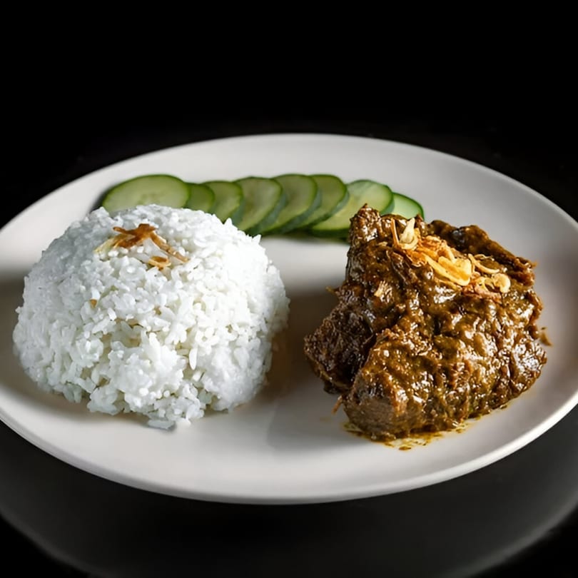 A white plate with a mound of white rice, sliced cucumbers, and a rich brown meat dish.